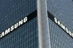 Corner of a glass office tower with large white SAMSUNG logos on two sides seeing the building at an angle.