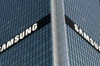 Corner of a glass office tower with large white SAMSUNG logos on two sides seeing the building at an angle.