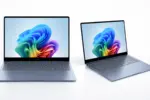 Two slim laptops open on a white surface, displaying a vibrant abstract wallpaper on their screens.