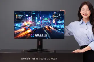 Woman posing with a large gaming monitor showing a neon-race car game on a desk. The display reads QD-OLED and 4K 360Hz markers are visible.